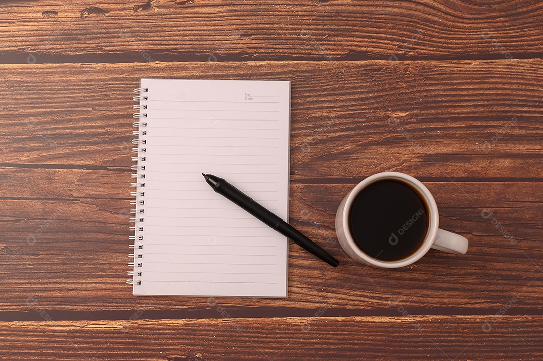 Café e um caderno estão em sua mesa.