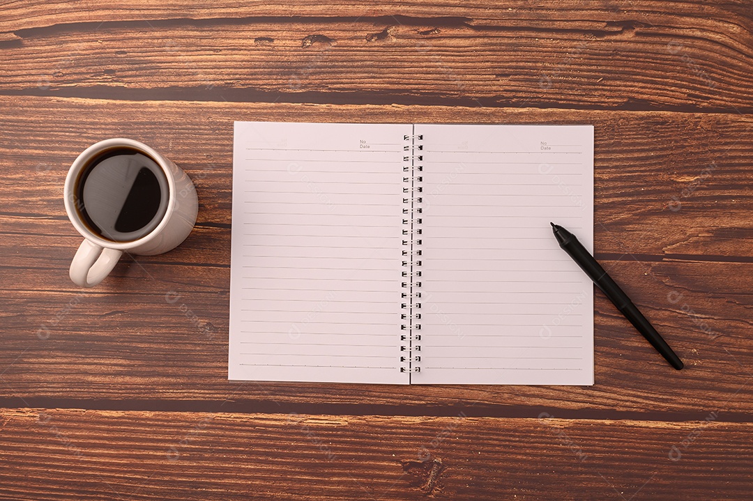 Café e um caderno  estão em sua mesa.