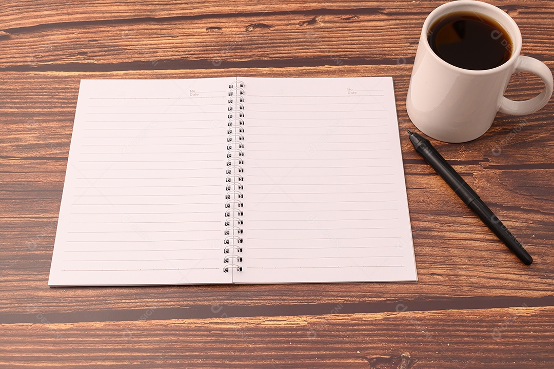 Café e um caderno estão em sua mesa.