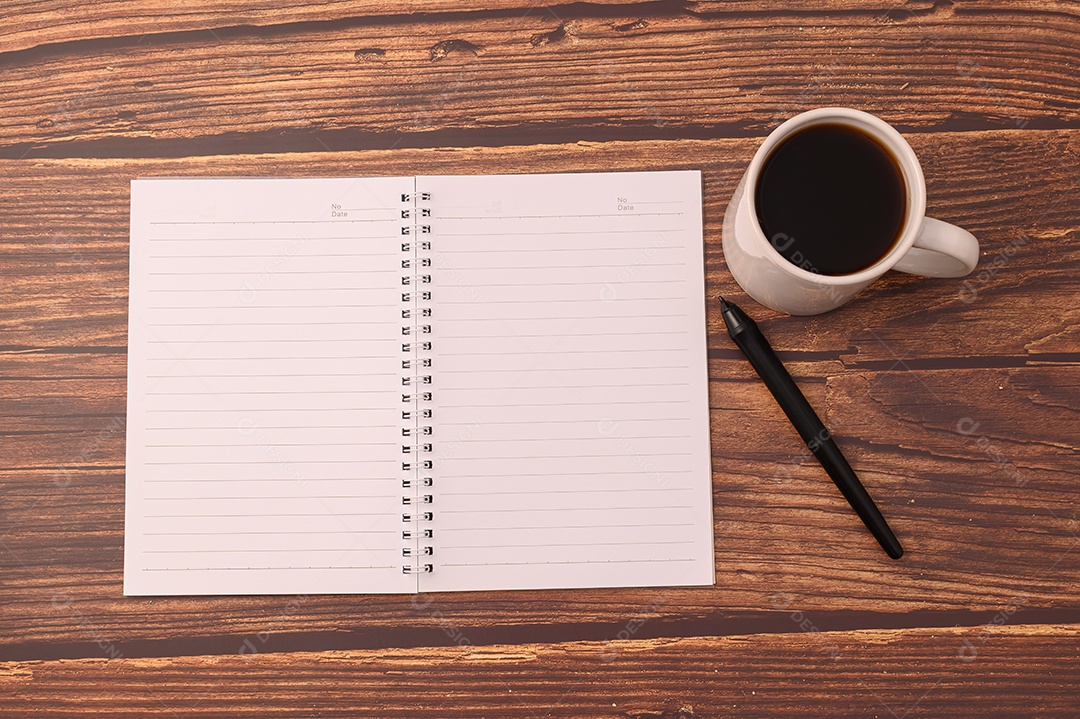 Café e um caderno estão em sua mesa.