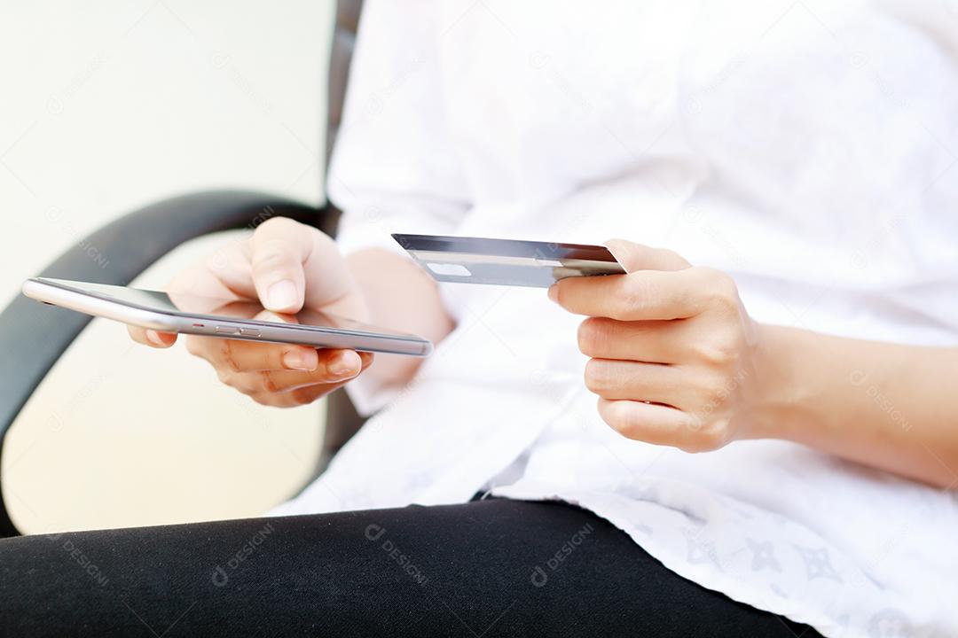 Asian woman using smartphone and credit card shopping online, selective focus on hand