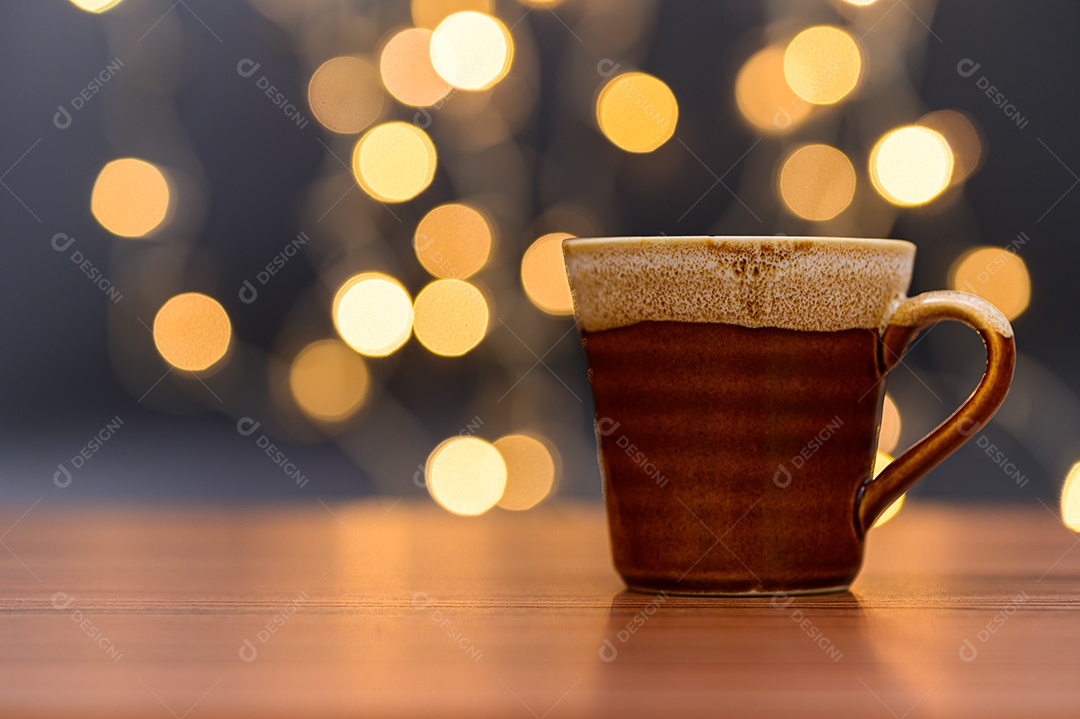 Caneca de café está sobre a mesa. Cenário de luzes de bokeh laranja