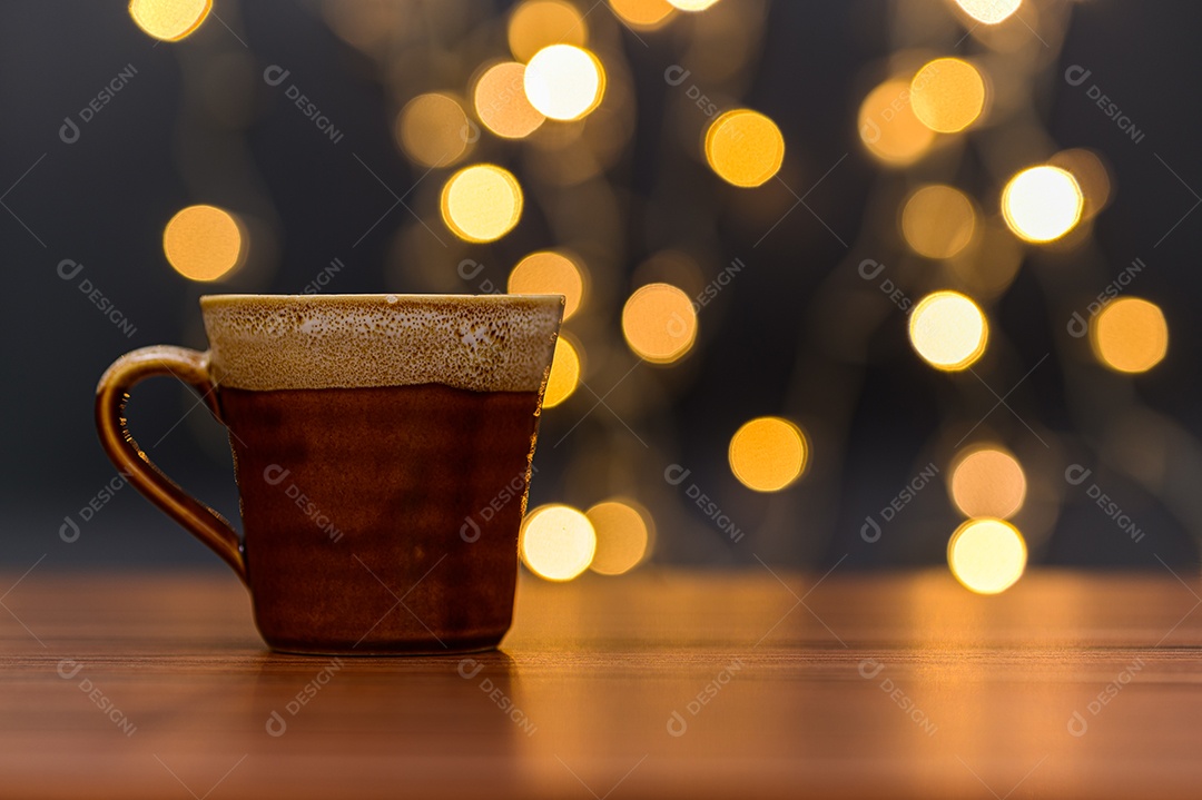Caneca de café está sobre a mesa. Cenário de luzes de bokeh laranja