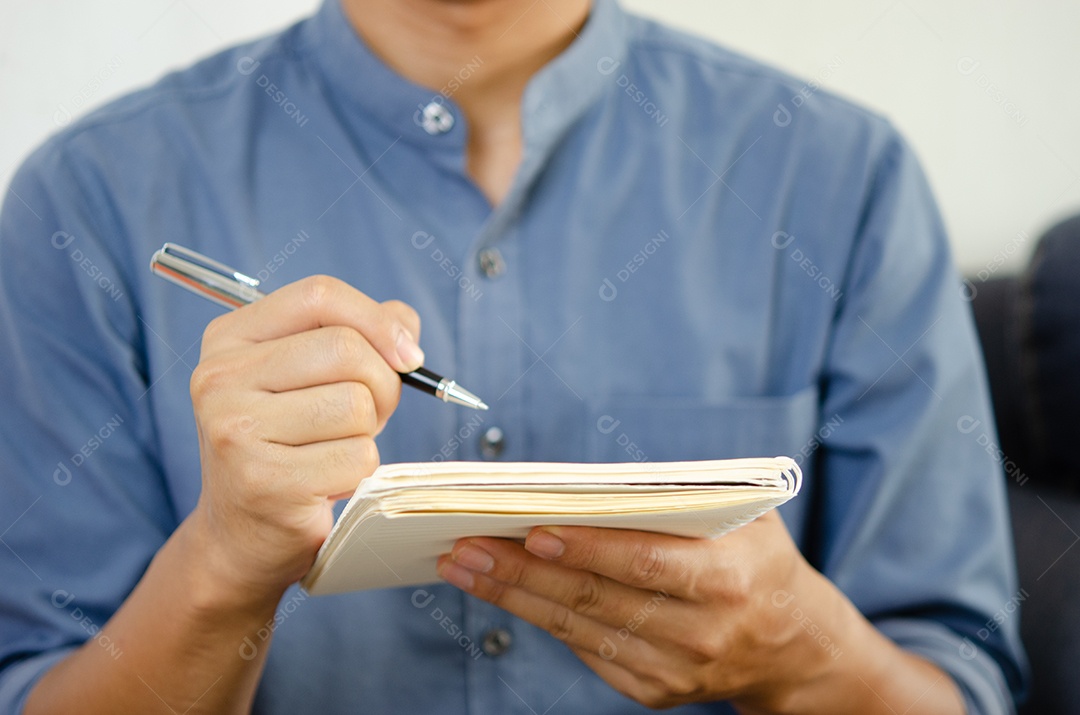 Empresário segurando uma caneta e um caderno para fazer anotações e planejar ideias.