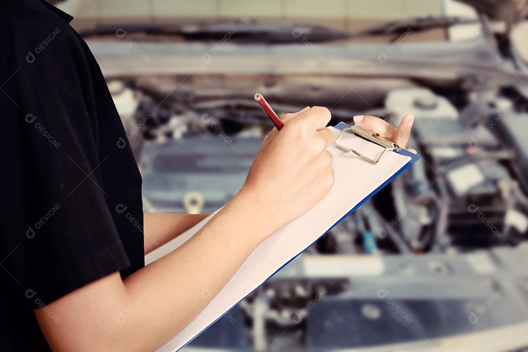 Retrato de uma jovem mecânica sorridente inspecionando um carro na oficina de automóveis