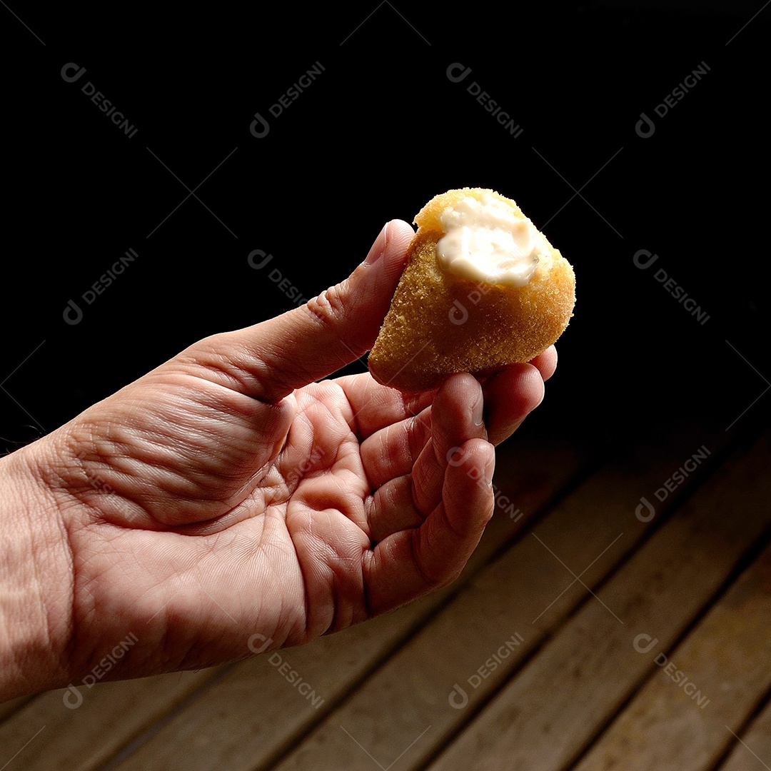 Mãos de pessoa segurando comida sobre fundo preto