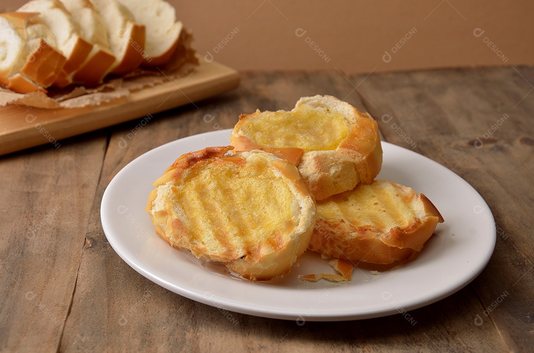 Pão na chapa sobre prato branco mesa madeira
