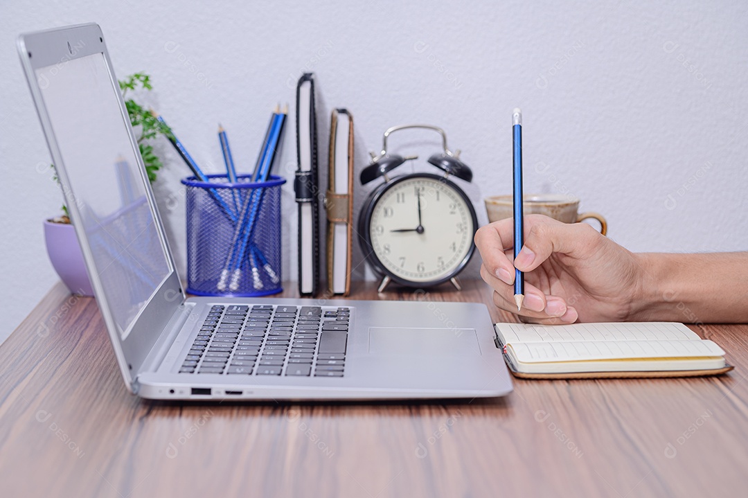 Mão faz anotações no livro na mesa da sala