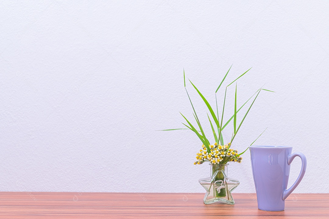 Canecas de café e vasos de flores estão em sua mesa.