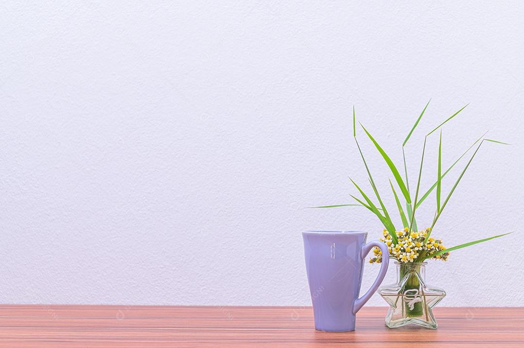 Canecas de café e vasos de flores estão em sua mesa.