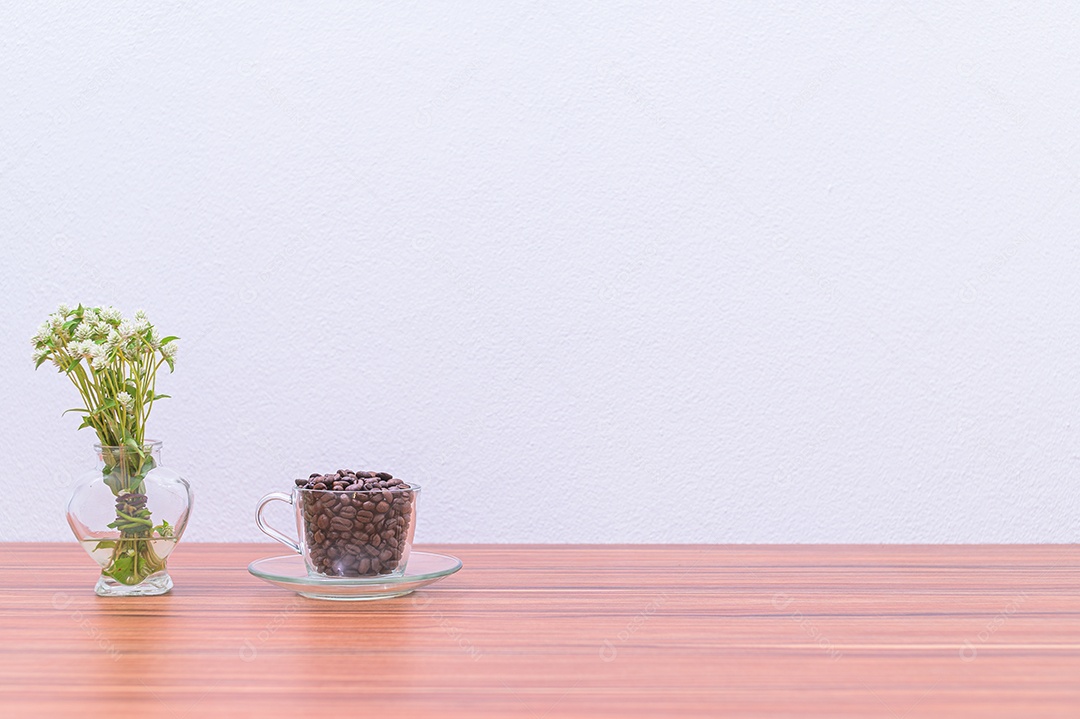 Canecas de café e vasos de flores estão em sua mesa.