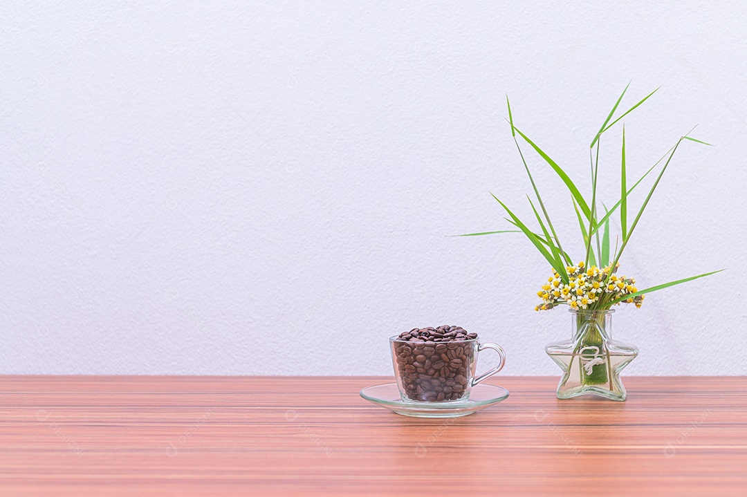 Canecas de café e vasos de flores estão em sua mesa.