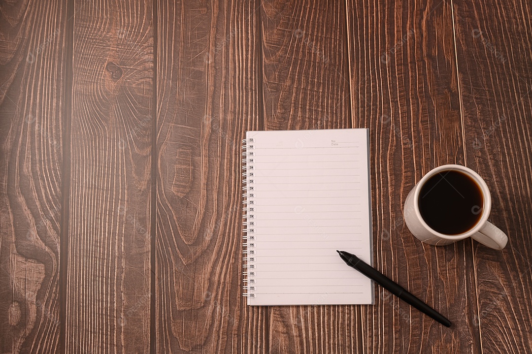 Café e um caderno estão em sua mesa.