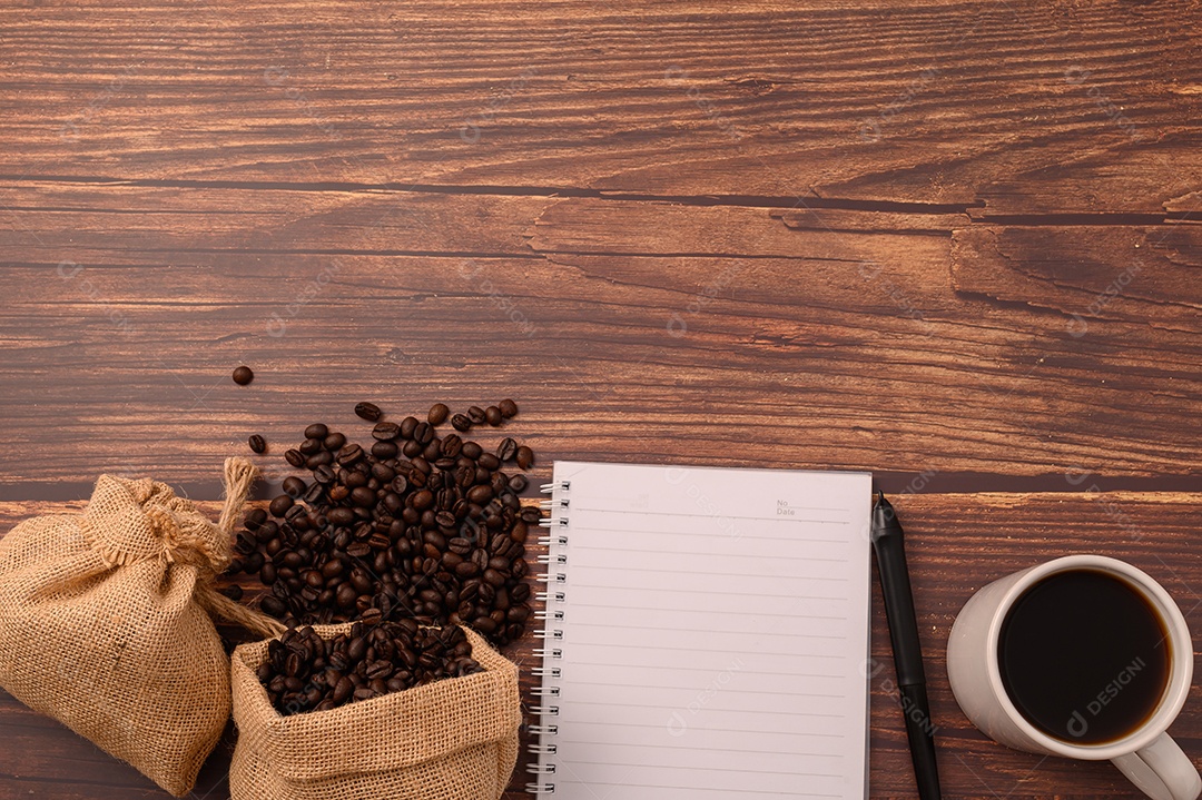 Café e um caderno estão em sua mesa.