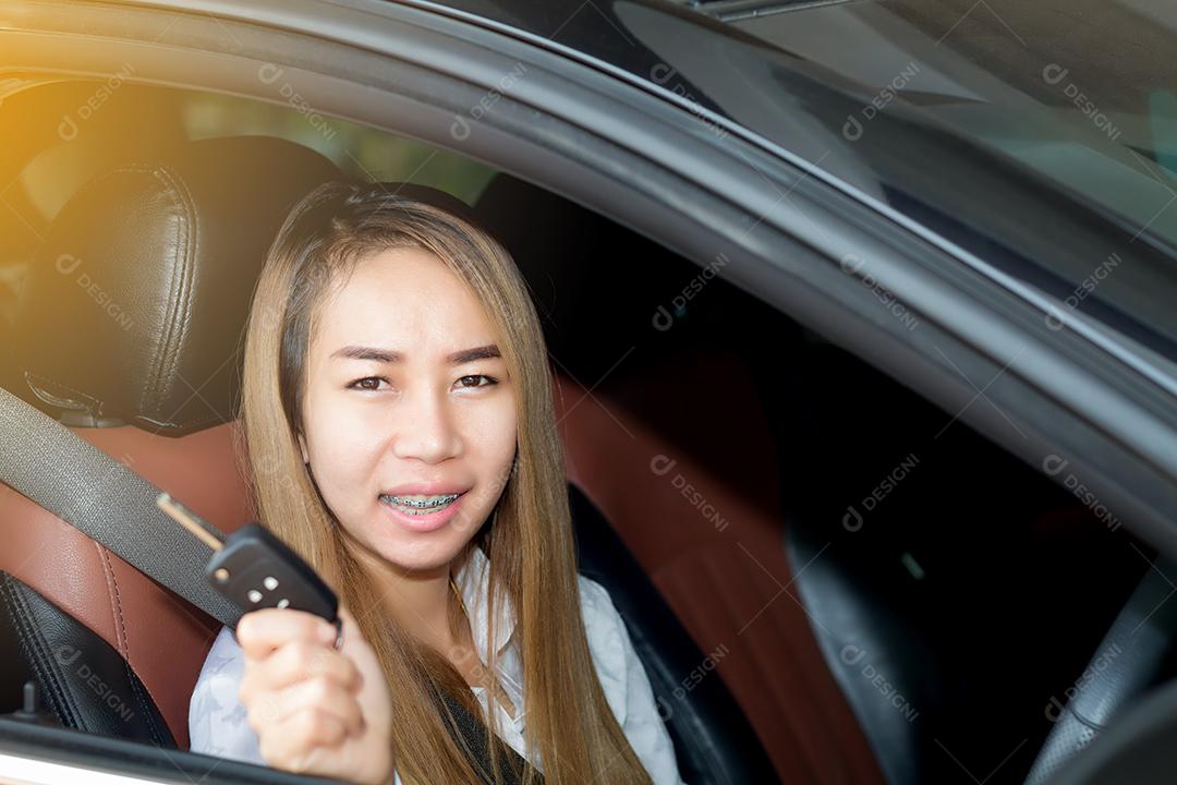 Mulher asiática estão segurando a chave para dirigir carros na estrada.