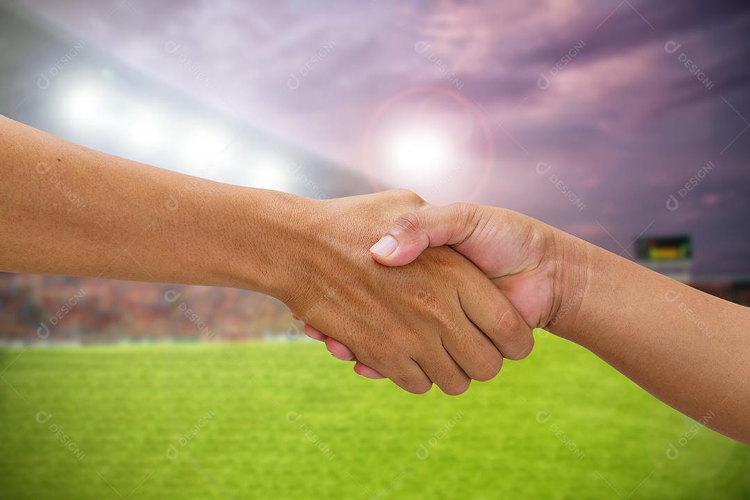 aperto de mão em um time adversário de negócios, apertando a mão no fundo do estádio de futebol