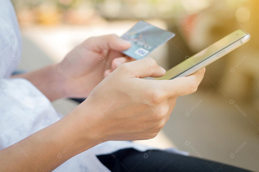 mulher asiática usando telefone e cartão de crédito compras on-line na luz solar