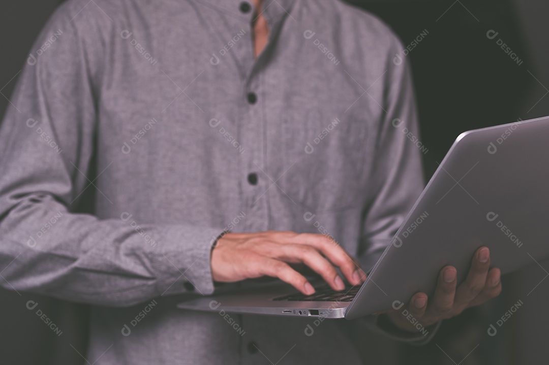 Homem segura e usa um notebook