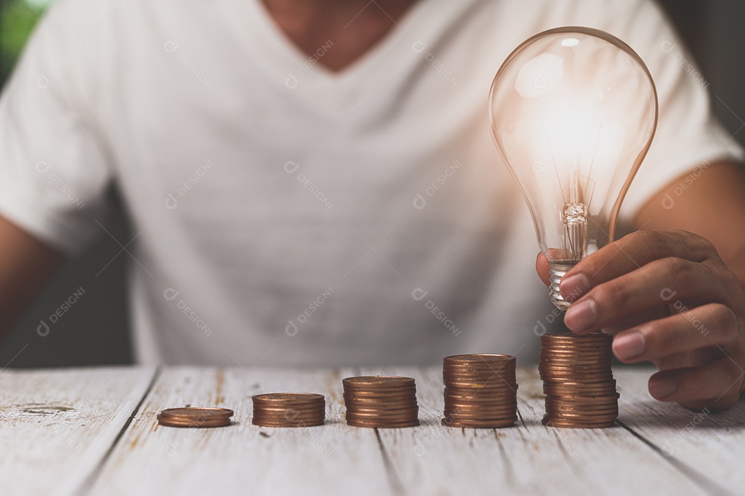 Empresário segurando ideia de pilha de dinheiro de lâmpada economizando energia