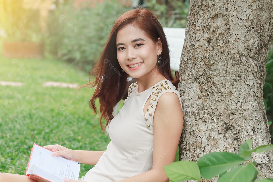 Mulher asiática lendo um livro no jardim para relaxar