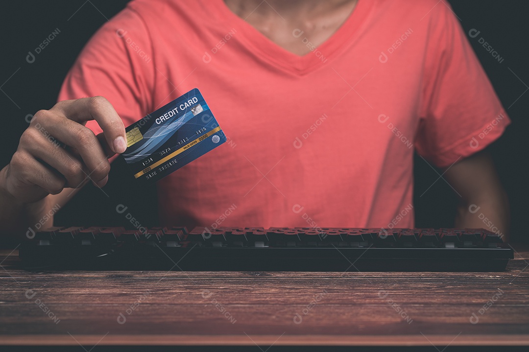 Homem está usando um cartão de crédito pelo computador