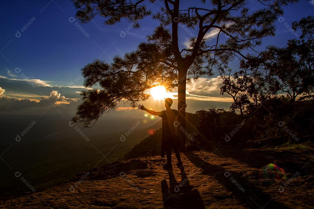 silhueta do homem mostra o braço para realizações bem sucedidas e comemorando o sucesso no pôr do sol e a silhueta do empresário com bandeira na montanha