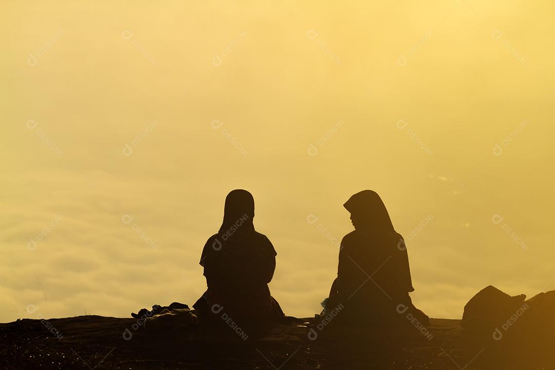 silhueta Casal romântico e sentar e assistir o nascer do sol na montanha.