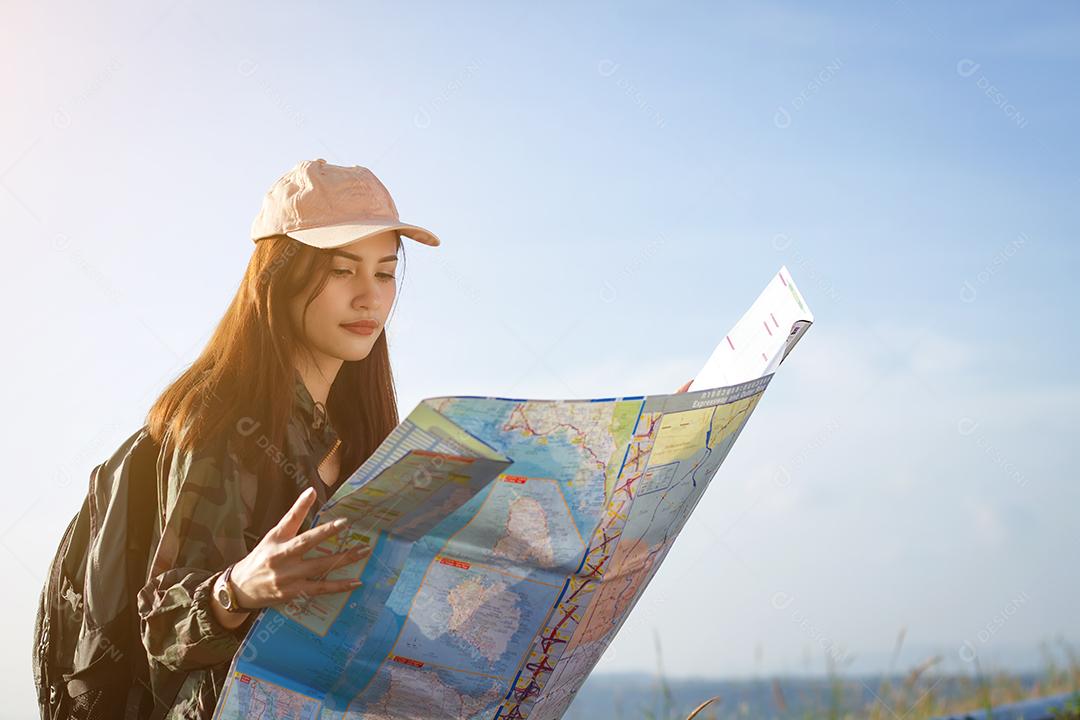 Mulheres asiáticas com mochila apreciando o pôr do sol no pico da montanha, olhando o mapa. Viajante turístico na paisagem montanhosa de fundo e luz solar em viagem