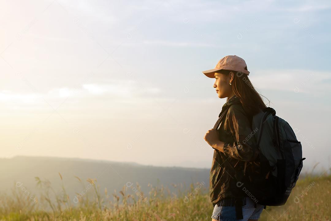 Mulher asiática de retrato mochila. Ela estava sorrindo e feliz em viajar no pico da montanha à beira-mar ao nascer do sol