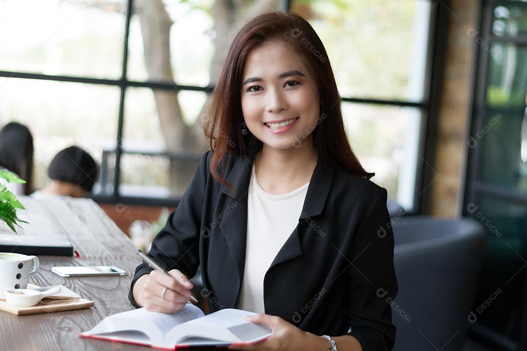 Empresária asiática sorrindo e lendo um livro para relaxar