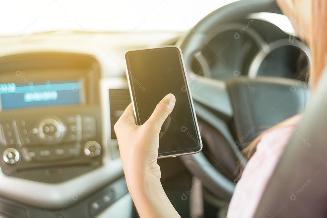 As mulheres asiáticas estão dirigindo carros e usando um smartphone na estrada.