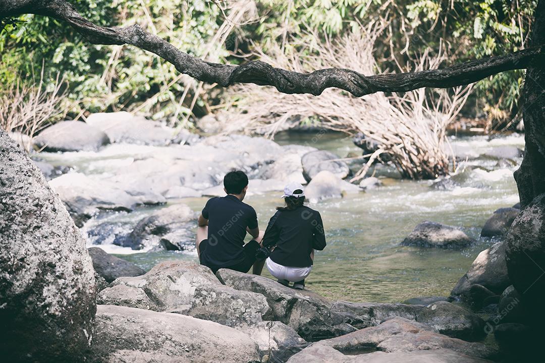 casal sentados juntos na cachoeira com felicidade e romance.