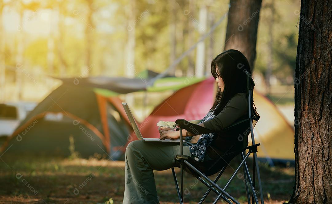 Mulher asiática estão jogando um notebook para trabalhar na floresta de férias.