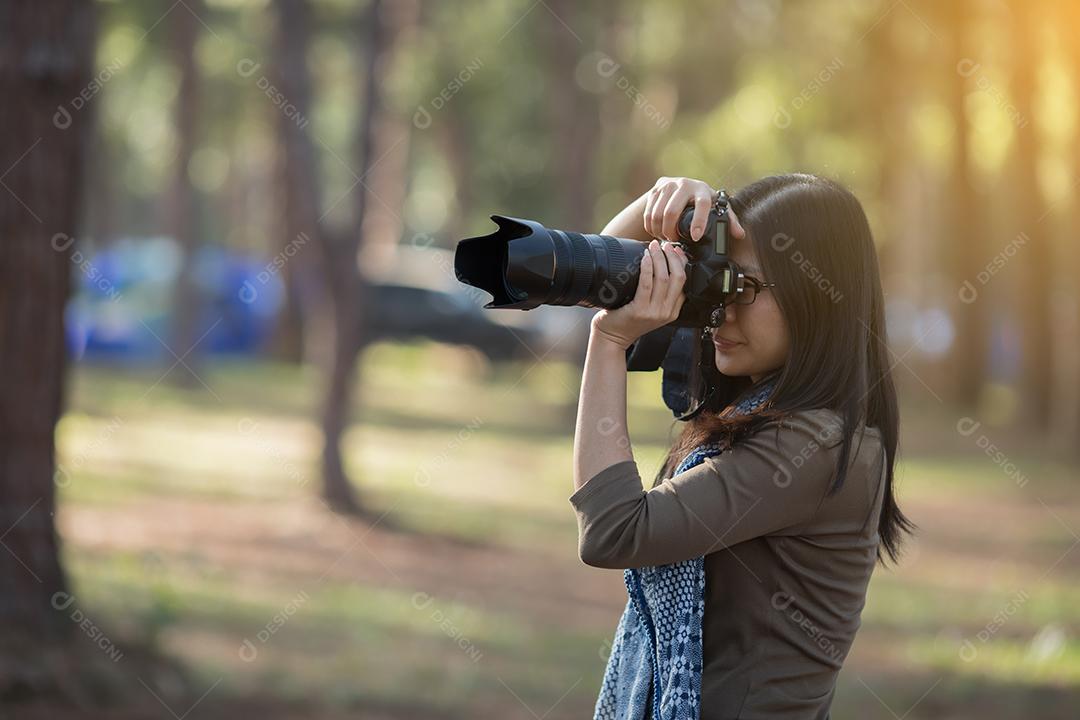 Fotógrafo de mulher segurando uma câmera em estado selvagem para tirar uma foto.