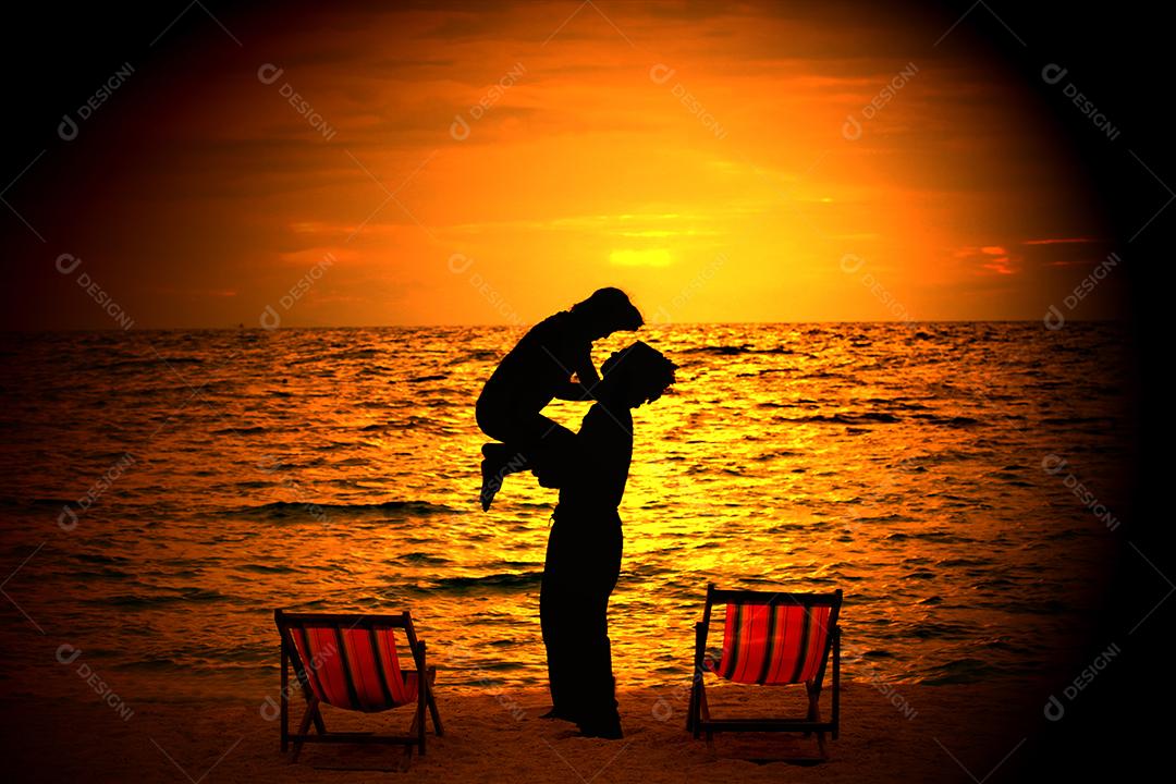 silhueta de jovem casal apaixonado abraçando na praia no pôr do sol