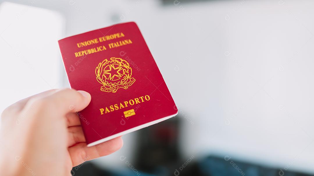 Mão segurando um passaporte italiano.