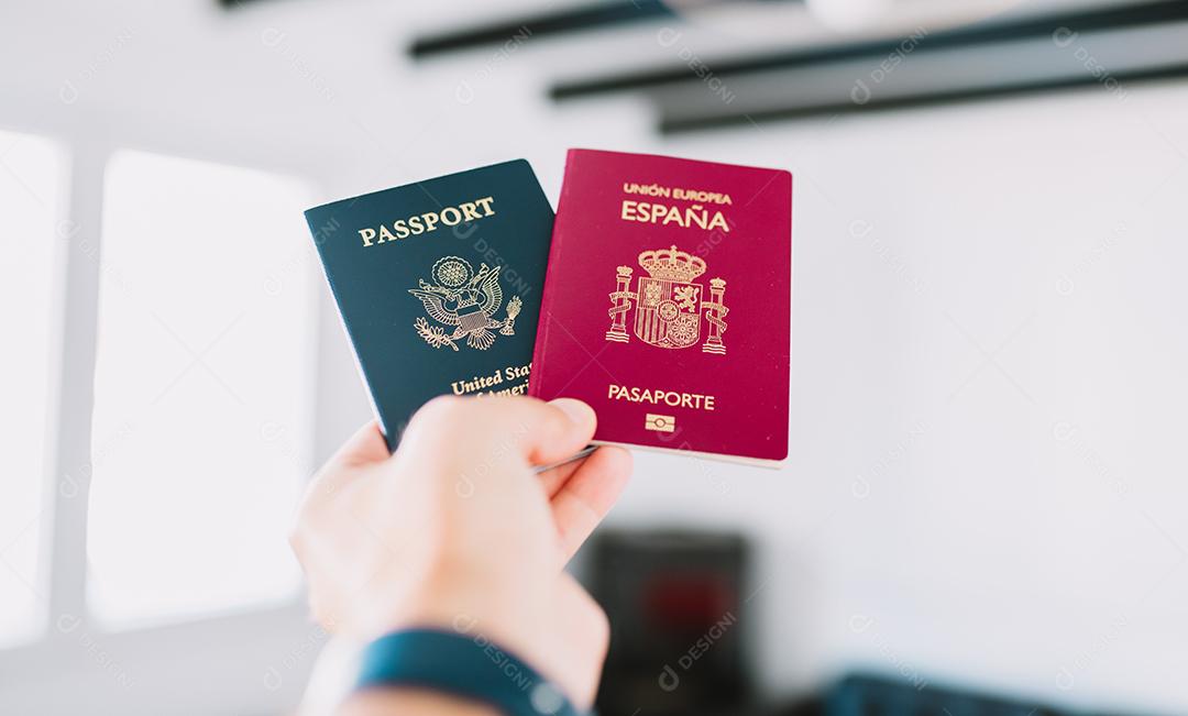 Mão segurando um passaporte europeu e americano.