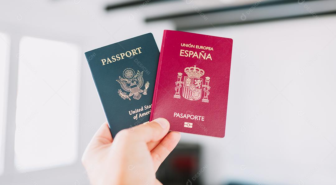 Mão segurando um passaporte europeu e americano.