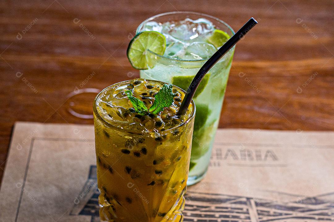 Caipirinha de maracujá ao lado de uma caipirinha de limão