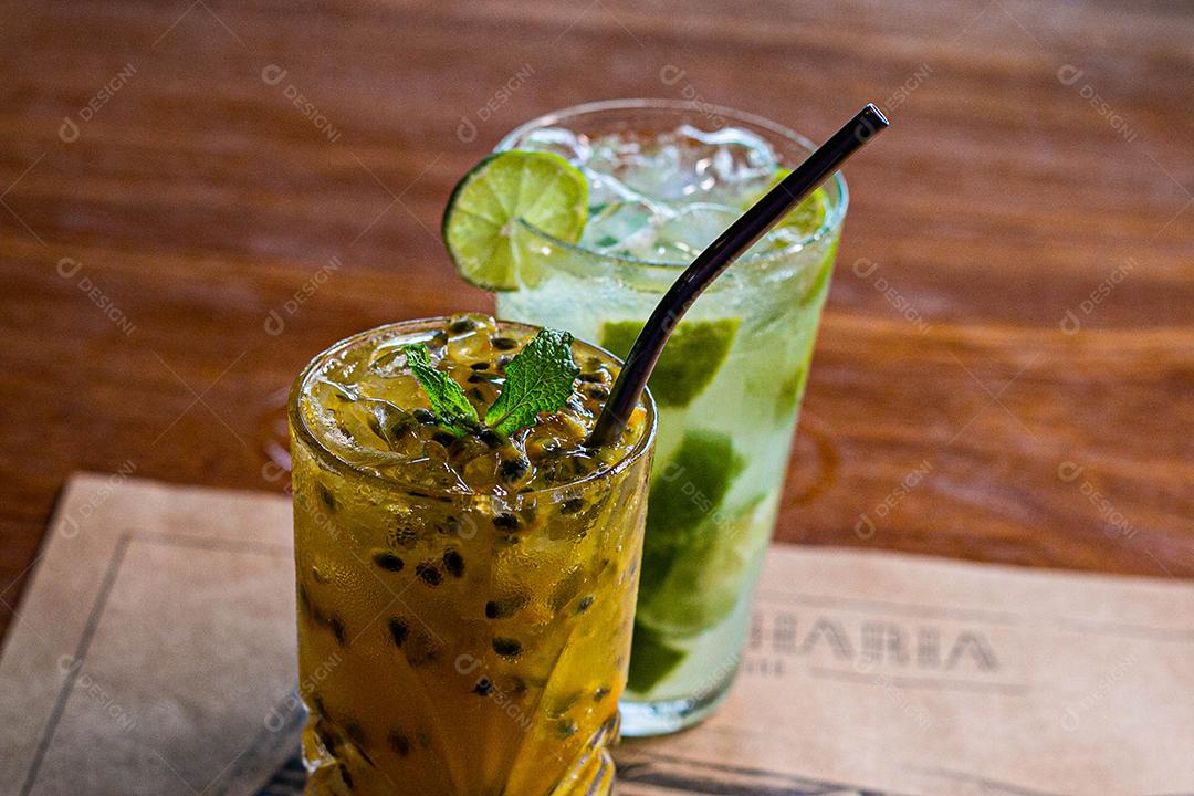 Caipirinha de maracujá ao lado de uma caipirinha de limão