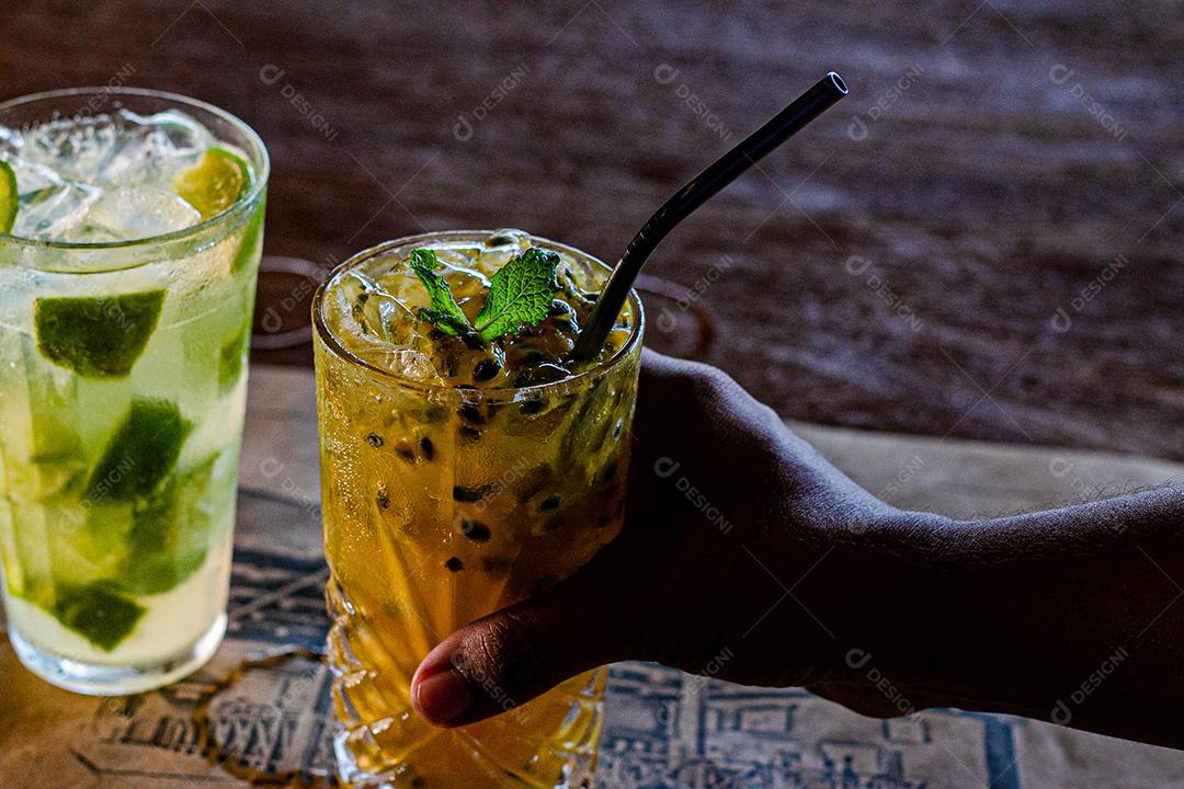 Caipirinha de maracujá ao lado de uma caipirinha de limão