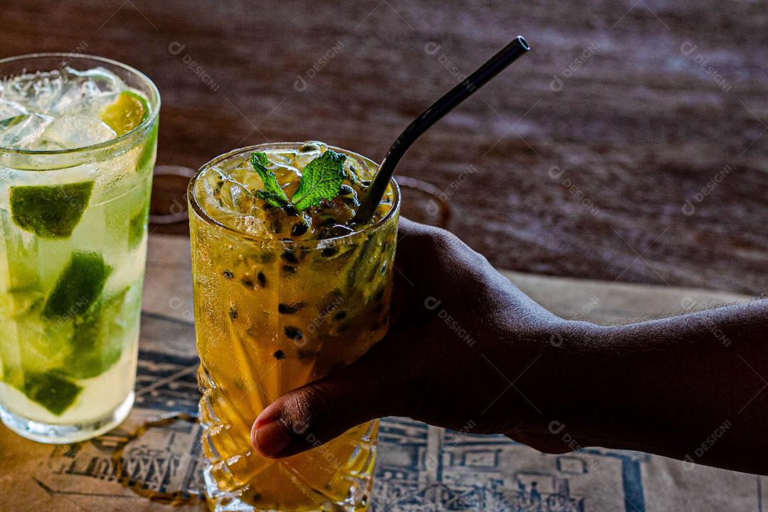 Caipirinha de maracujá ao lado de uma caipirinha de limão