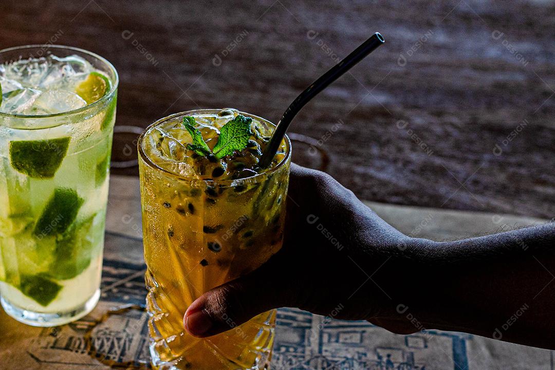 Caipirinha de maracujá ao lado de uma caipirinha de limão