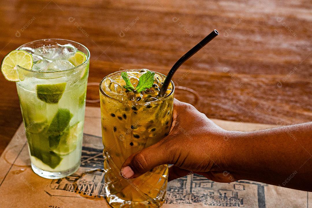 Caipirinha de maracujá ao lado de uma caipirinha de limão