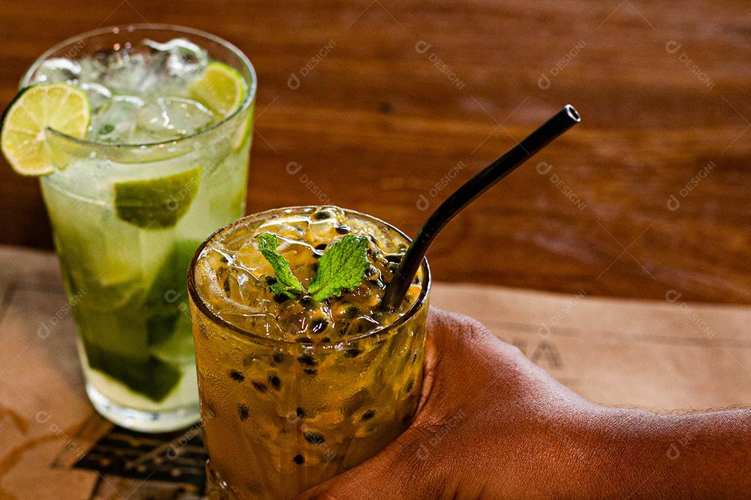 Caipirinha de maracujá ao lado de uma caipirinha de limão