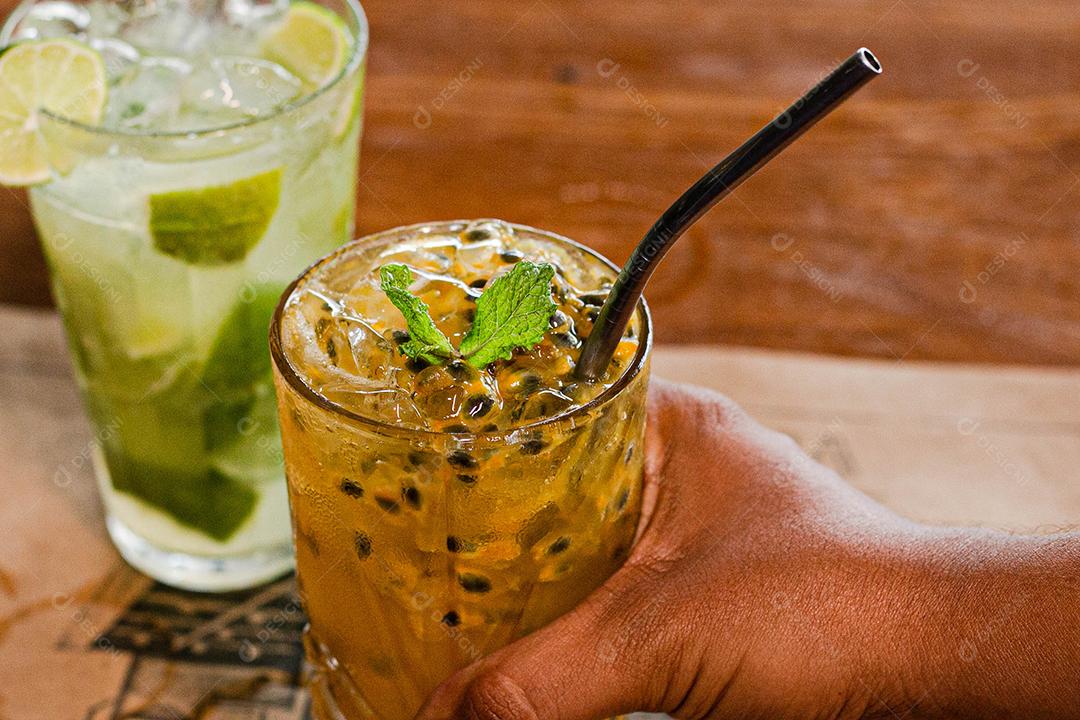 Caipirinha de maracujá ao lado de uma caipirinha de limão