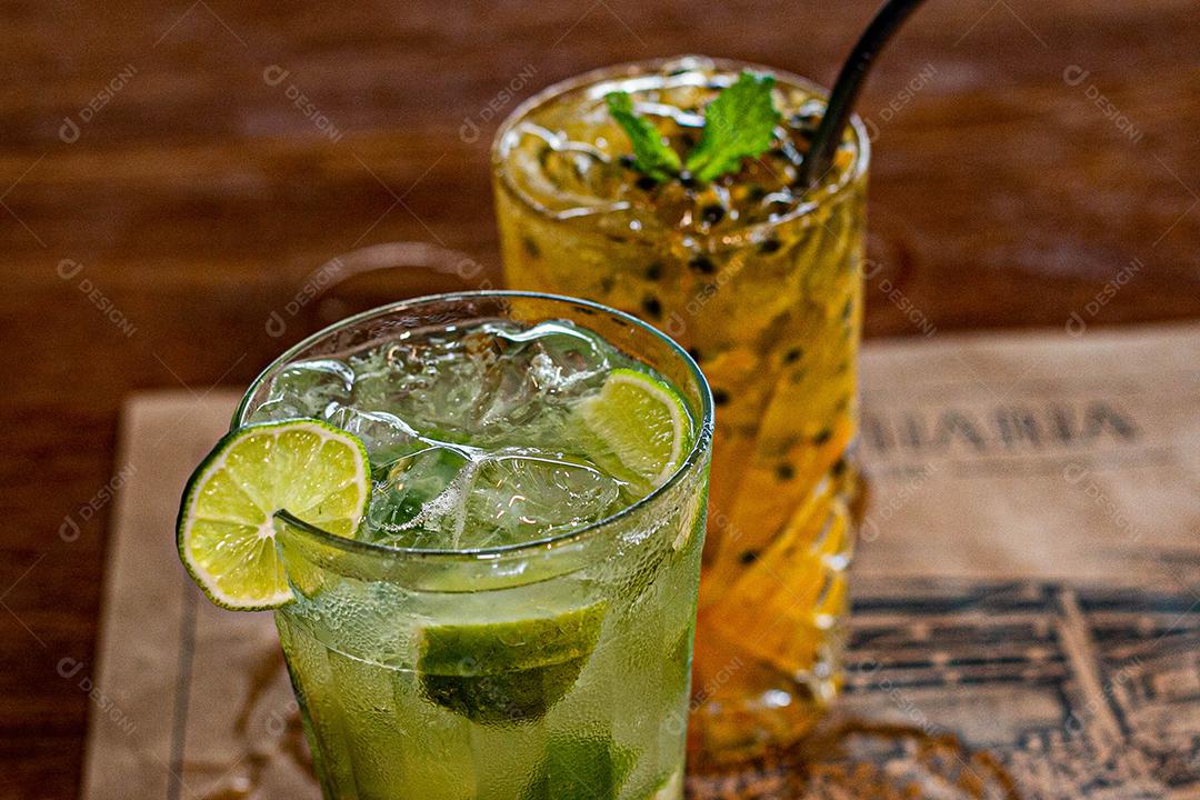 Caipirinha de maracujá ao lado de uma caipirinha de limão