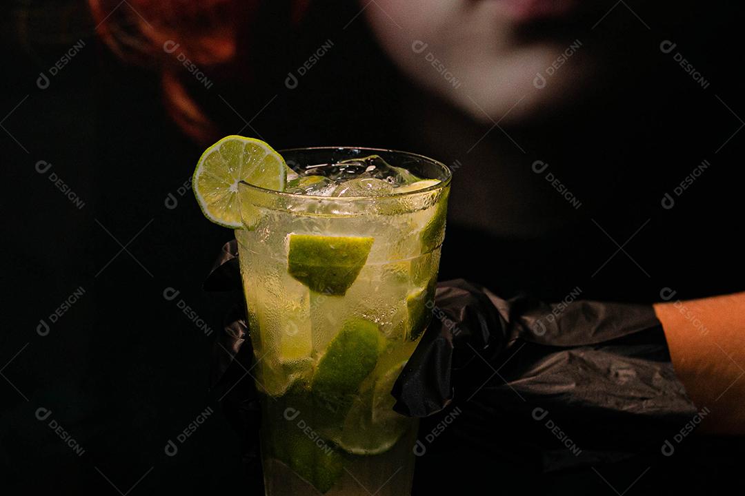 Caipirinha de limão com cubos de gelo em fundo preto