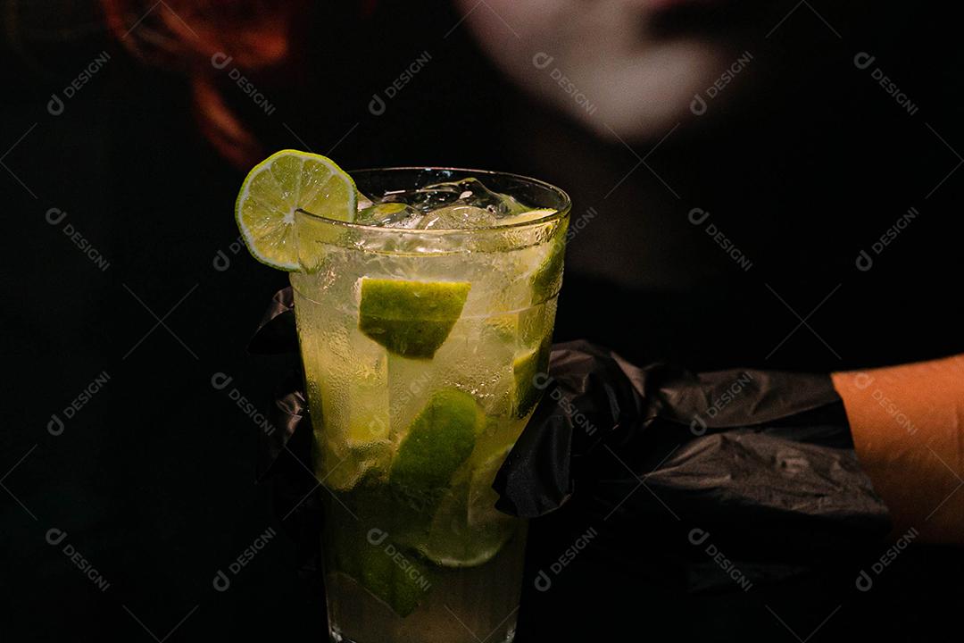 Caipirinha de limão com cubos de gelo em fundo preto