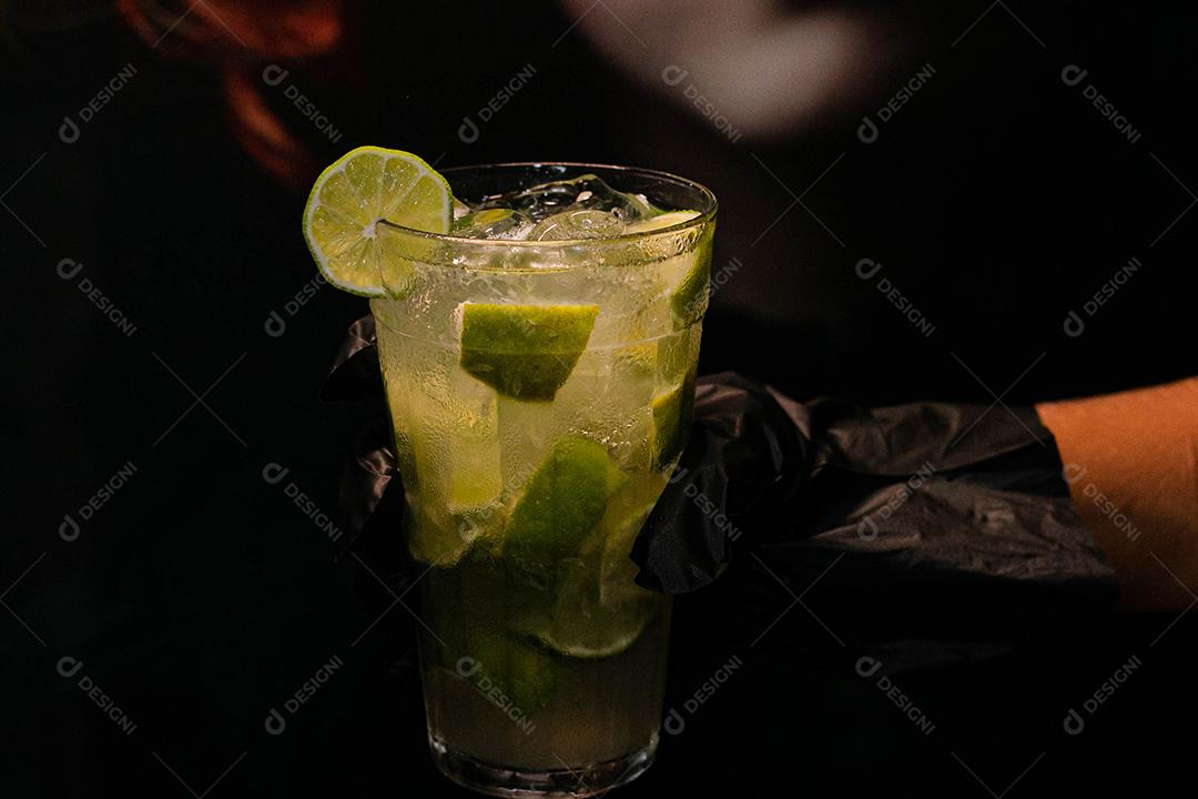 Caipirinha de limão com cubos de gelo em fundo preto